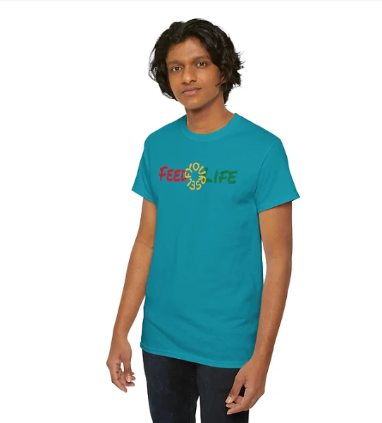 A person wears a teal t-shirt with a vibrant circular design on the front featuring the words “FEEL,” “LOVE,” and “LIFE.” Each word is rendered in a different color—red for “FEEL,” yellow for “LOVE,” and green for “LIFE”—creating a visually engaging and emotionally uplifting message. The circular arrangement draws the eye and reinforces the interconnectedness of emotion, compassion, and vitality.