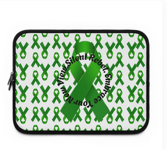 A laptop sleeve features a white background patterned with green awareness ribbons. At the center, a larger ribbon is encircled by the phrase “Silent Rebel. Embrace Your New Vieux.” The design blends advocacy with personal transformation, using visual repetition and symbolic language to promote mental health awareness and a shift in perspective.