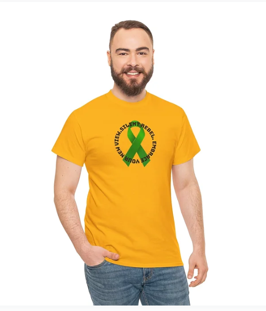 A man wears a bright yellow T-shirt featuring a green awareness ribbon at the center. Surrounding the ribbon is bold black text that reads: “EMBRACE YOUR INNER REBEL. STAY SILENT. STAY TRUE.” The man smiles confidently against a plain white background, embodying the shirt’s message of individuality, quiet strength, and mental health advocacy.