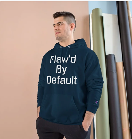 Man wearing a navy hoodie with 'Flaw'd By Default' text, standing against a wall with paint samples.