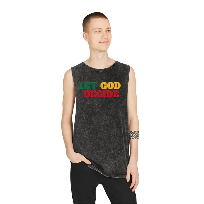 A person stands with one hand in their pocket, wearing a sleeveless black acid-washed shirt that reads "LET GOD DECIDE." The phrase is split into three colors: "LET" in green, "GOD" in yellow, and "DECIDE" in red. The individual has a short haircut and displays a patterned armband tattoo on their left arm. The minimalist background keeps the focus on the shirt’s bold design, which blends spiritual messaging with edgy streetwear style.