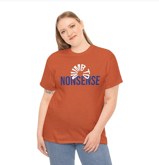 A person stands against a plain white background wearing a rust-colored T-shirt with a bold graphic design. The word "NONSENSE" is printed in large blue capital letters across the chest. Above it, a circular motif spells out "DUMB" in curved lettering, adding a layered visual element. The person is dressed in blue jeans and poses with one hand on the hip, presenting a relaxed and expressive look. The shirt’s design combines irony and humor, making it a standout piece for novelty or statement fashion.